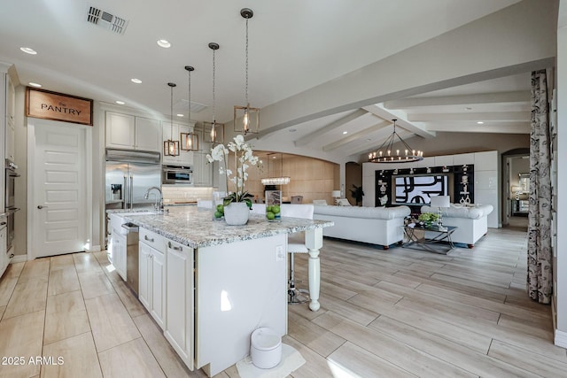 kitchen with light stone countertops, hanging light fixtures, a large island, and lofted ceiling with beams