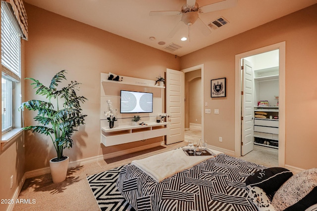 bedroom with a spacious closet, ceiling fan, and light colored carpet