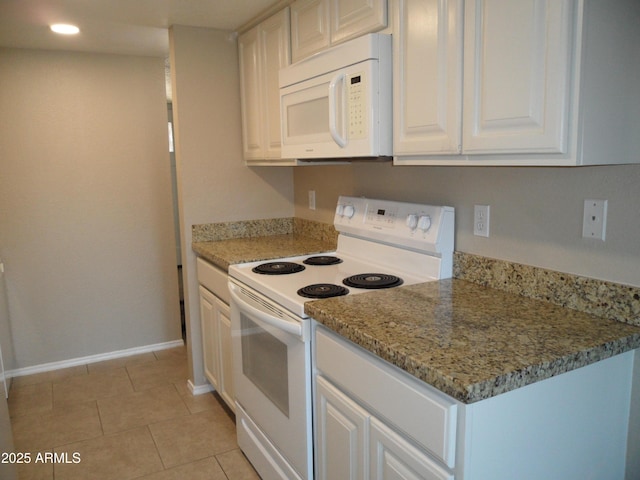 kitchen with white appliances, white cabinets, light tile patterned floors, and light stone counters