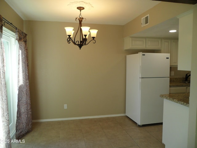 kitchen featuring white fridge, light tile patterned floors, pendant lighting, white cabinetry, and an inviting chandelier