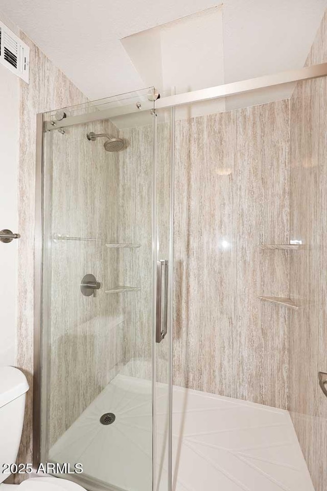 bathroom with a shower with shower door and toilet