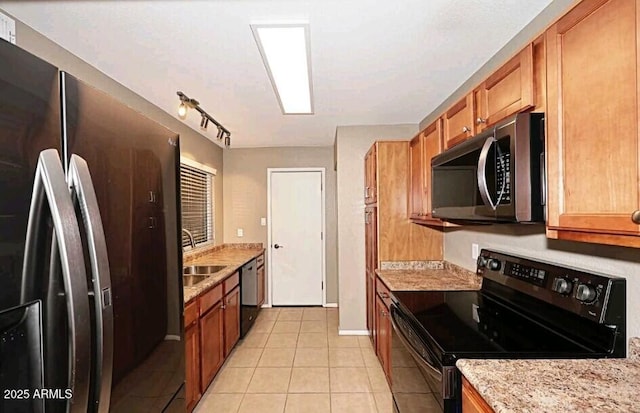 kitchen featuring light tile patterned floors, sink, appliances with stainless steel finishes, light stone counters, and track lighting