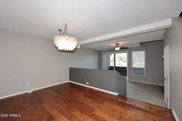 spare room with beamed ceiling, ceiling fan with notable chandelier, and hardwood / wood-style floors