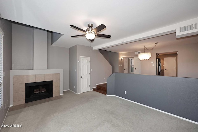 unfurnished living room featuring light carpet, ceiling fan with notable chandelier, and a tile fireplace