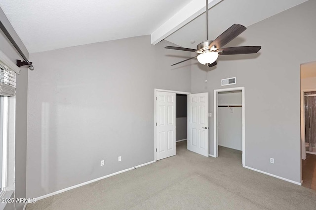 unfurnished bedroom with beamed ceiling, light colored carpet, ceiling fan, and high vaulted ceiling