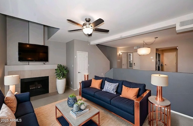 living room featuring a tiled fireplace and ceiling fan