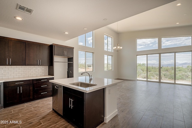 kitchen with a sink, dishwasher, wood finished floors, a chandelier, and light countertops