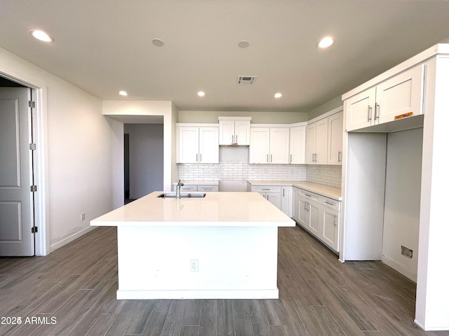 kitchen with a sink, a center island with sink, recessed lighting, tasteful backsplash, and white cabinetry