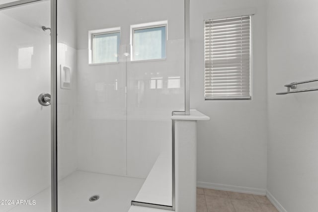 bathroom featuring a stall shower, tile patterned flooring, and baseboards