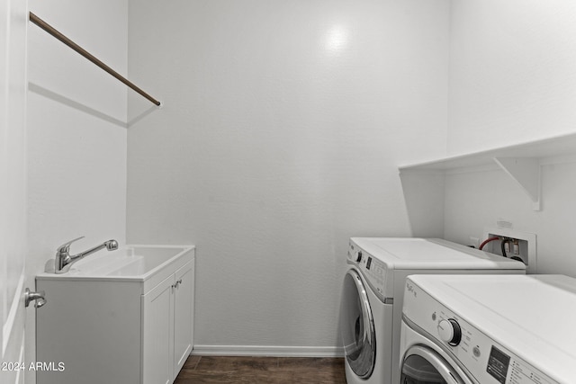 washroom with cabinet space, baseboards, dark wood finished floors, washing machine and dryer, and a sink