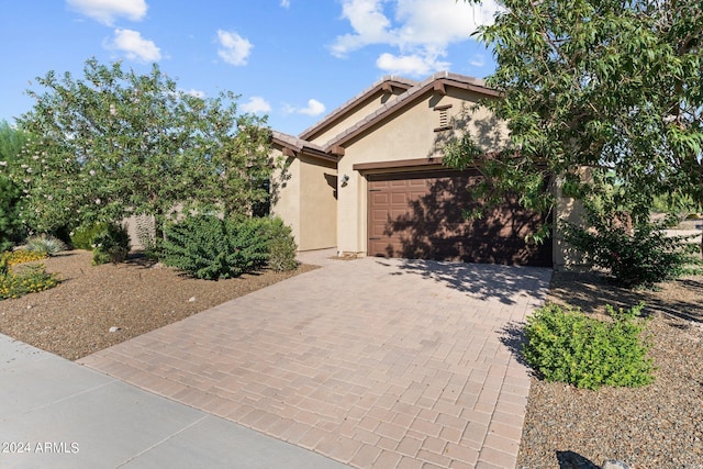 view of front of house with an attached garage, a tile roof, decorative driveway, and stucco siding