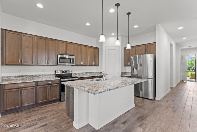 kitchen with stainless steel appliances, dark wood finished floors, pendant lighting, and a sink