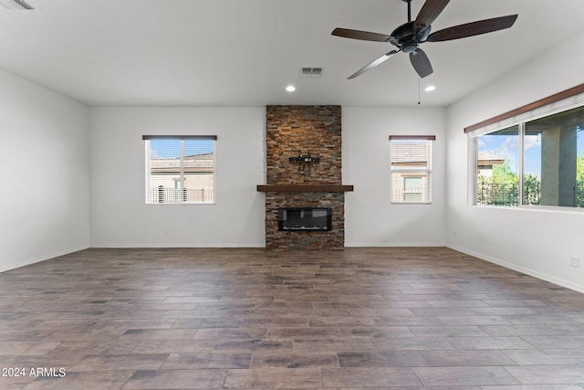 unfurnished living room with visible vents, a fireplace, wood finished floors, and a wealth of natural light