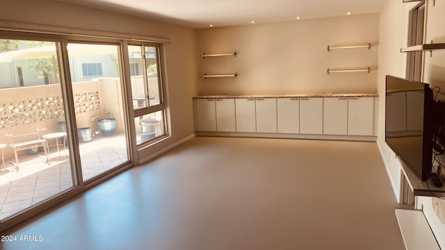 spare room featuring finished concrete flooring, visible vents, and baseboards