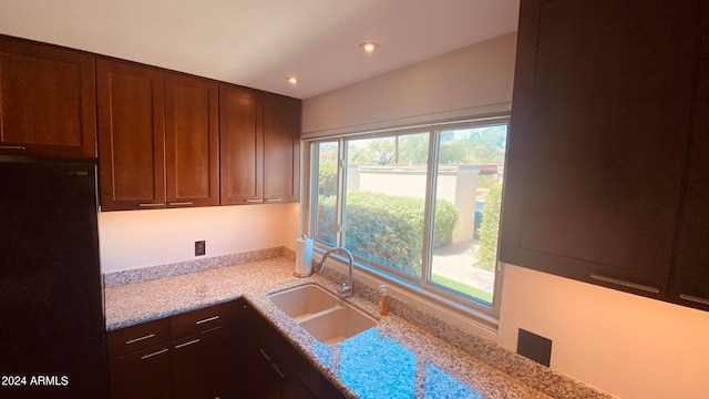 kitchen with sink, fridge, and light stone counters