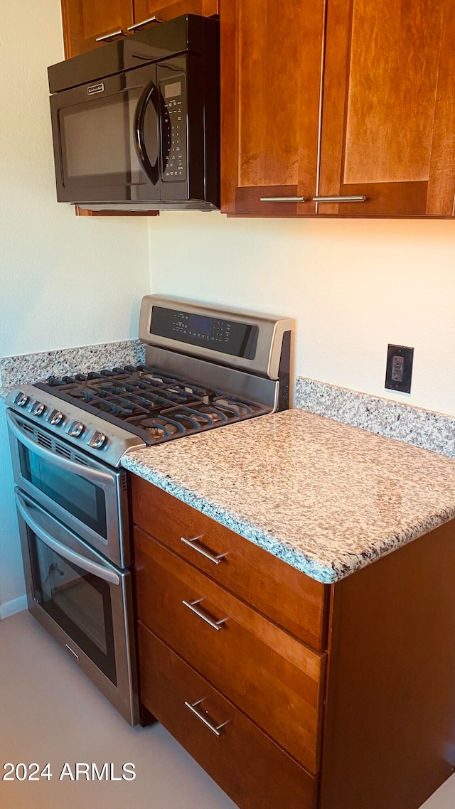 kitchen featuring range with two ovens and light stone countertops