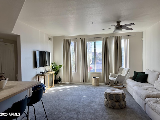 carpeted living room featuring ceiling fan and a textured ceiling