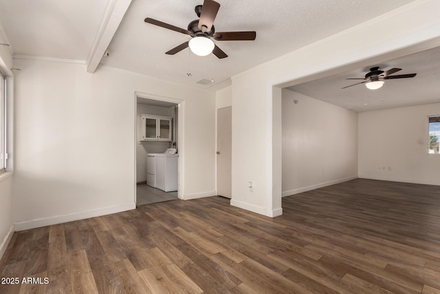 empty room featuring washing machine and dryer, ceiling fan, wood finished floors, and baseboards