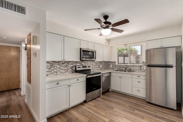 kitchen featuring a sink, tasteful backsplash, visible vents, light countertops, and appliances with stainless steel finishes