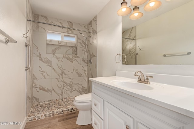 bathroom with an inviting chandelier, a shower stall, vanity, toilet, and wood finished floors