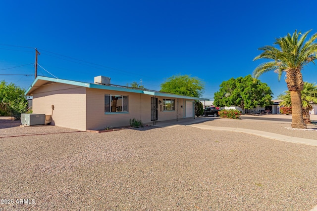 view of front of property with central AC unit, brick siding, concrete driveway, and a garage