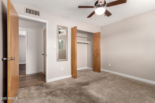 unfurnished bedroom featuring visible vents, a textured ceiling, a closet, and carpet