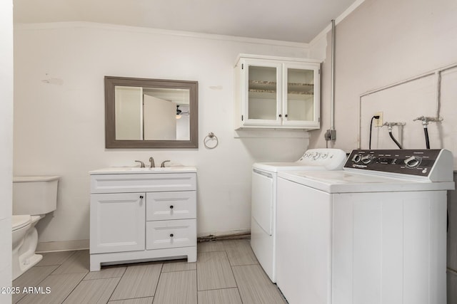 washroom featuring separate washer and dryer, laundry area, crown molding, and a sink