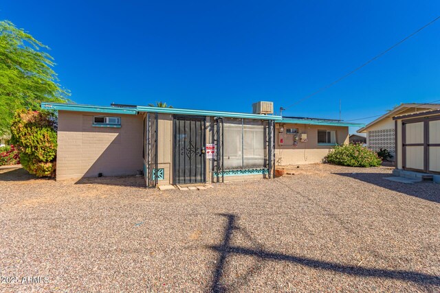 rear view of property with an outdoor structure, central AC unit, concrete block siding, and a storage shed
