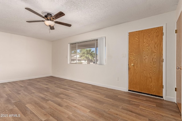 spare room with a textured ceiling, wood finished floors, ceiling fan, and baseboards