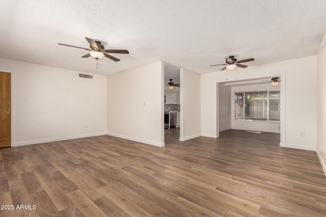 unfurnished living room with visible vents, wood finished floors, a ceiling fan, and a textured ceiling