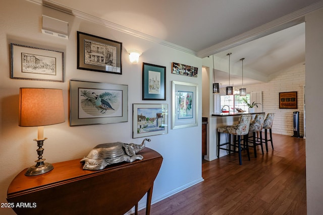 hallway featuring dark wood-type flooring, lofted ceiling, ornamental molding, and brick wall