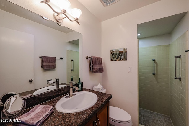 bathroom featuring toilet, a tile shower, and vanity