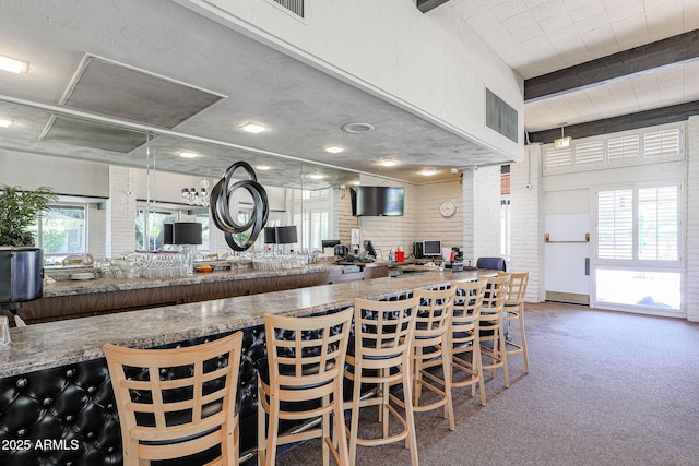 kitchen featuring plenty of natural light, a breakfast bar, carpet, and kitchen peninsula