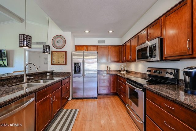 kitchen featuring pendant lighting, sink, stainless steel appliances, and dark stone counters