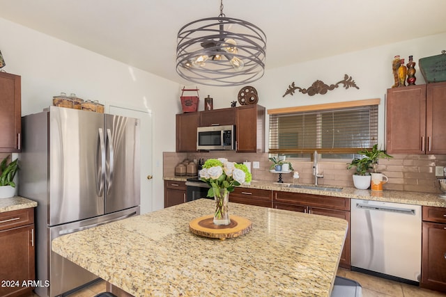 kitchen featuring decorative backsplash, appliances with stainless steel finishes, sink, pendant lighting, and a kitchen island