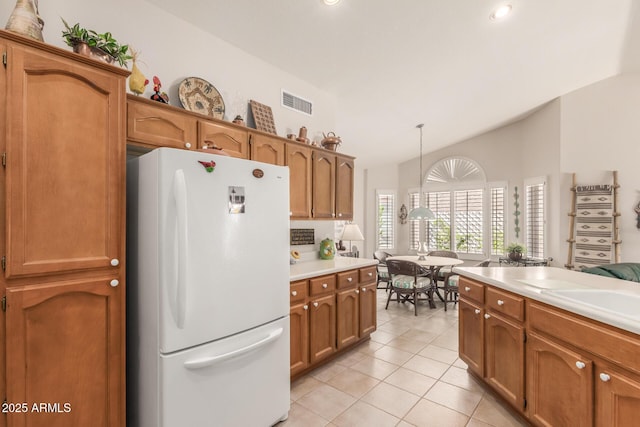 kitchen with lofted ceiling, sink, hanging light fixtures, light tile patterned flooring, and white fridge