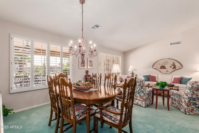 carpeted dining area featuring a notable chandelier and a wealth of natural light