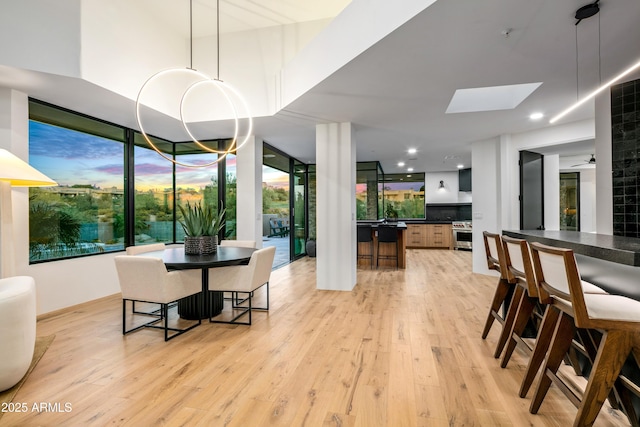 dining space with light wood finished floors, a skylight, recessed lighting, and an inviting chandelier