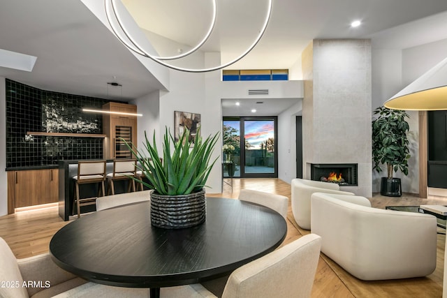 dining area with a tiled fireplace, wood finished floors, and visible vents