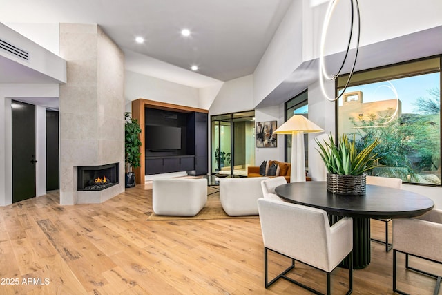 dining space with a fireplace, wood finished floors, and recessed lighting