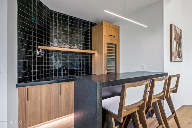 bar with wet bar, a sink, light wood finished floors, and decorative backsplash