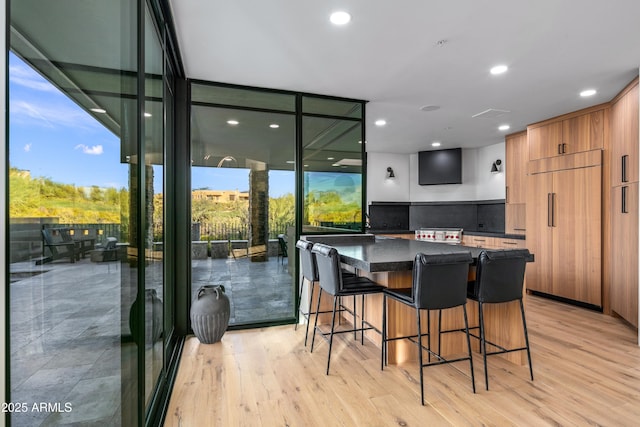 kitchen with dark countertops, a large island, modern cabinets, expansive windows, and light wood-style floors