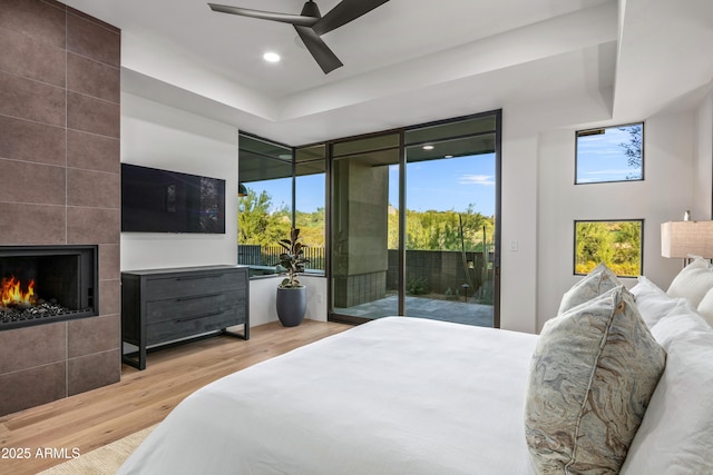 bedroom with recessed lighting, a fireplace, wood finished floors, a ceiling fan, and access to exterior