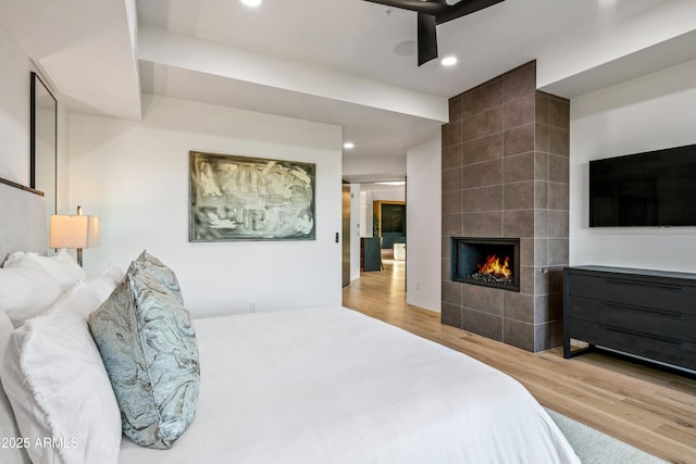 bedroom with a tile fireplace, recessed lighting, and wood finished floors