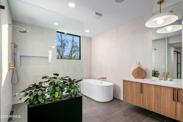 bathroom with tile walls, a freestanding bath, vanity, tile patterned flooring, and walk in shower