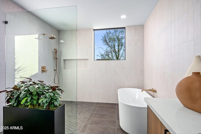 full bathroom featuring walk in shower, a freestanding bath, tile walls, and tile patterned floors