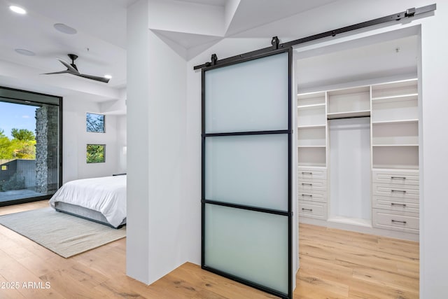 bedroom with access to exterior, light wood finished floors, and a barn door