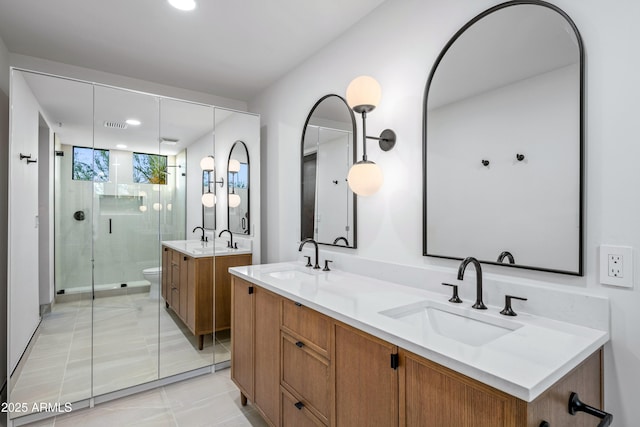 bathroom featuring double vanity, a stall shower, and a sink