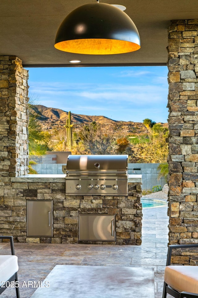 view of patio / terrace with an outdoor kitchen, area for grilling, fence, and a mountain view