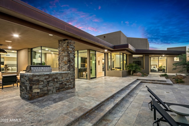 patio terrace at dusk featuring exterior kitchen